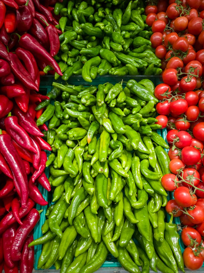Colorful and fresh peppers and tomatoes in a market, showcasing organic produce.